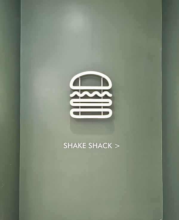 Shake Shack 店面照片，招牌酪梨綠牆面和經典LOGO，超級可愛好拍