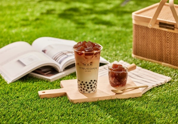 珍煮丹菜單推薦飲品「波波粿粿鮮奶茶」，杯中裝滿Q彈的黑糖珍珠與手作黑糖粉粿