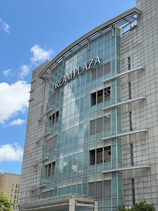 台北信義區新百貨 Dream Plaza 的建築外觀，白天陽光照射在現代風格的玻璃帷幕上。