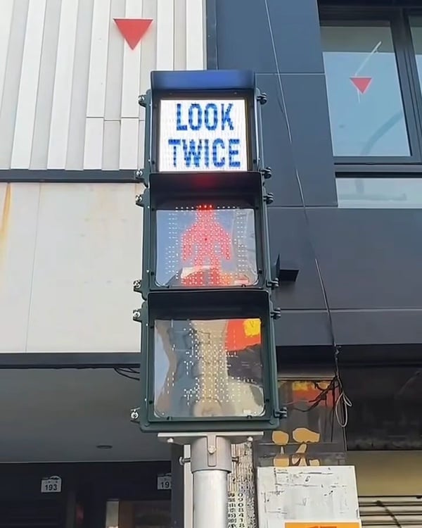  高雄市限定的 TWICE 主題交通號誌小綠人，行人號誌燈上顯示「LOOK TWICE」和「TWICE 2025 KAOHSIUNG」字樣。