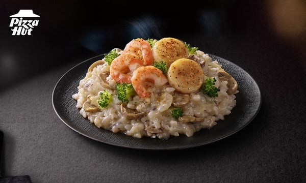 必勝客推薦菜單松露鮮蝦干貝燉飯，以紙包封烤方式呈現，飯上有鮮蝦與干貝