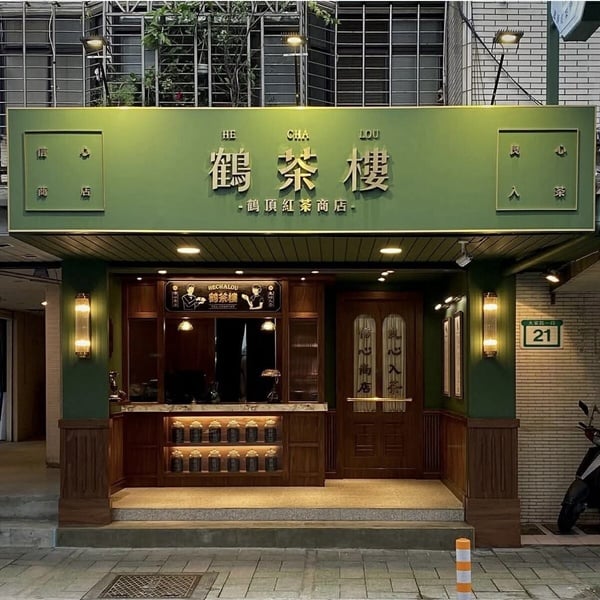 鶴茶樓經典金色系 LOGO，背景為墨綠色磁磚，呈現復古新潮的品牌風格。