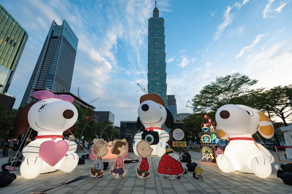 巨型史努比充氣玩偶在台北市政府前草地上展出，背景為台北101大樓